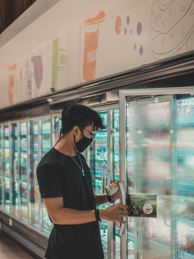 man grabbing an item from a reach-in refrigerator