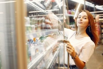 woman reaching into commercial fridge for a beverage